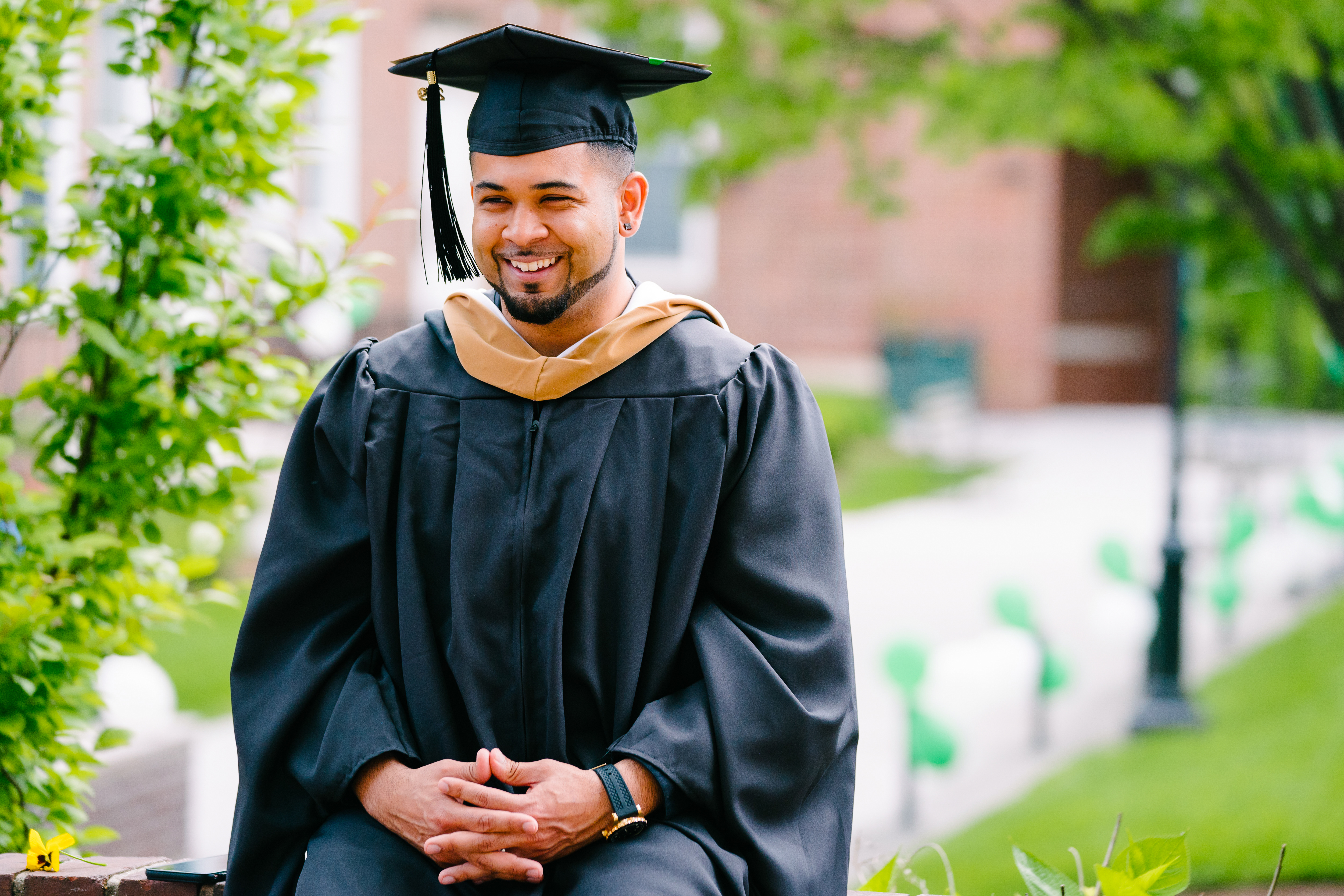 male student wearing graduation cap and gown and smiling