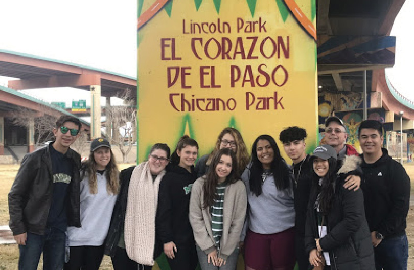 Students on El Paso LOVE Trip in a group photograph in front of sign that reads "Lincoln Park: El Corazon de El Paso