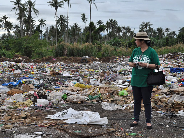 Susan Gallardo looking at pile of garbage
