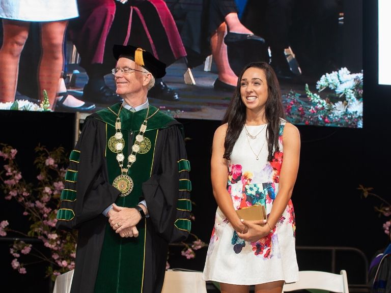 emma kaishian smiling on stage with president o'donnell