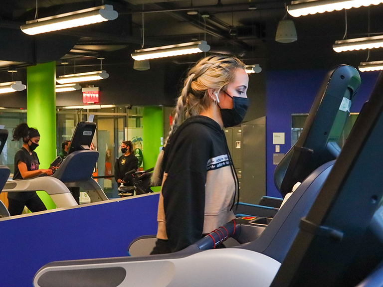 woman wearing mask working out on fitness center equipment