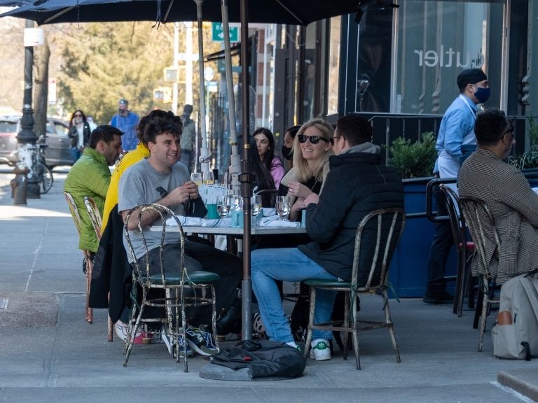 men and women eating at restaurant outdoors in new york city